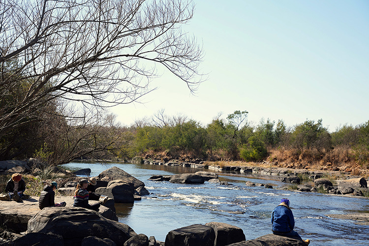 Camp 6 • Living Water - Guests resting on the rocks at the river