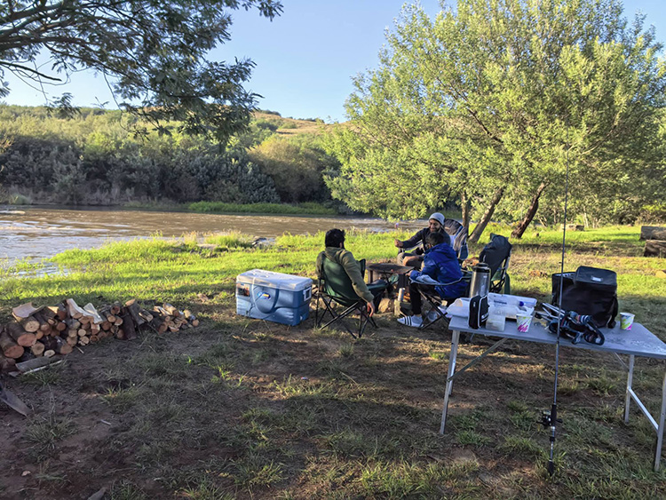 Camp 6 • Living Water - Camp chairs and fishing gear on the riverbank