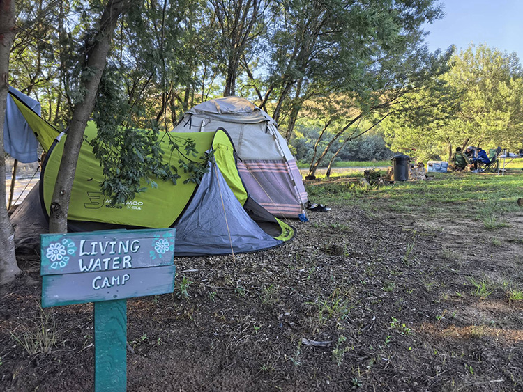 Camp 6 • Living Water - Living Water camp sign beside a pitched tent